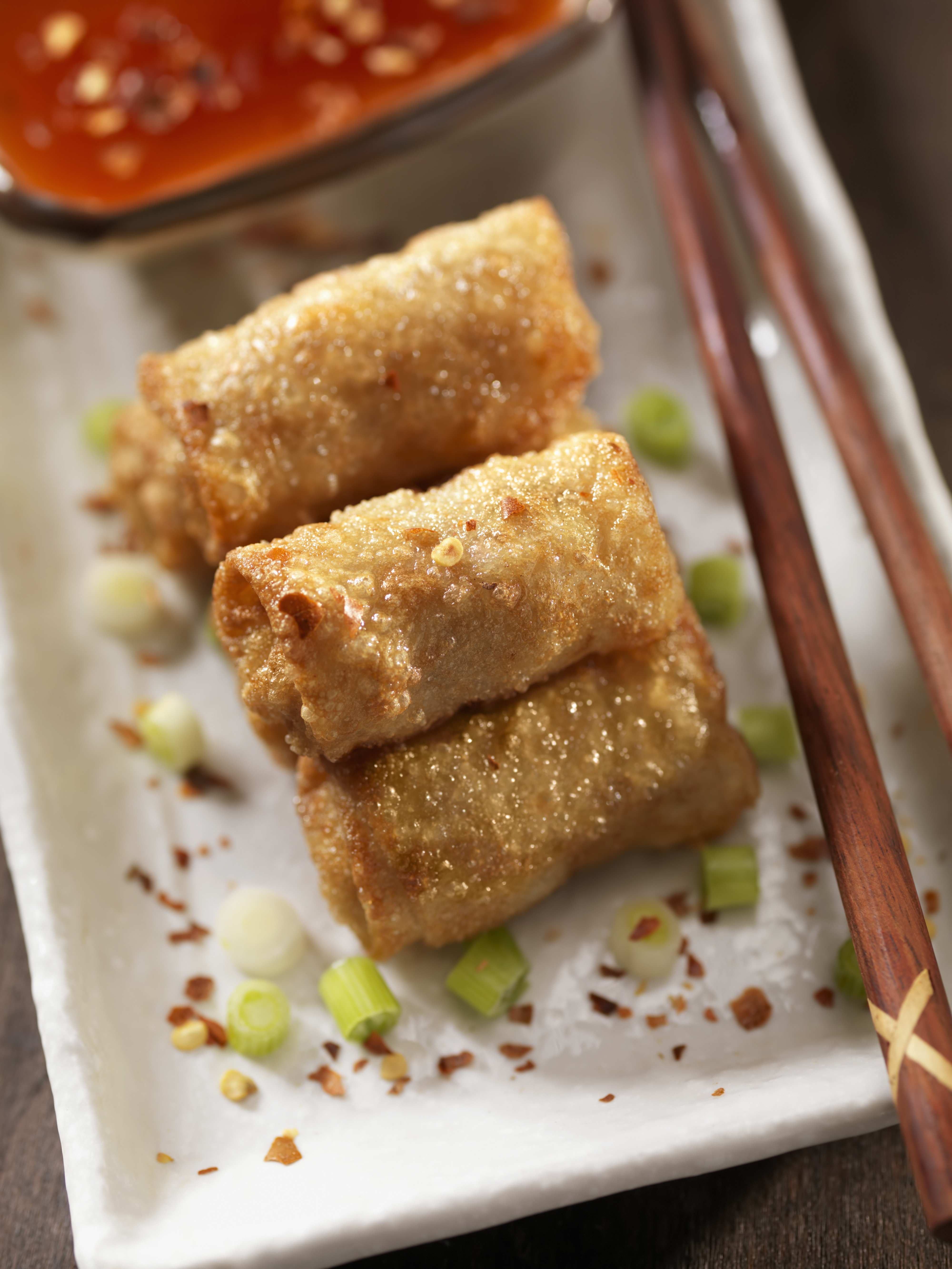 Crispy egg rolls on a plate with dipping sauce.